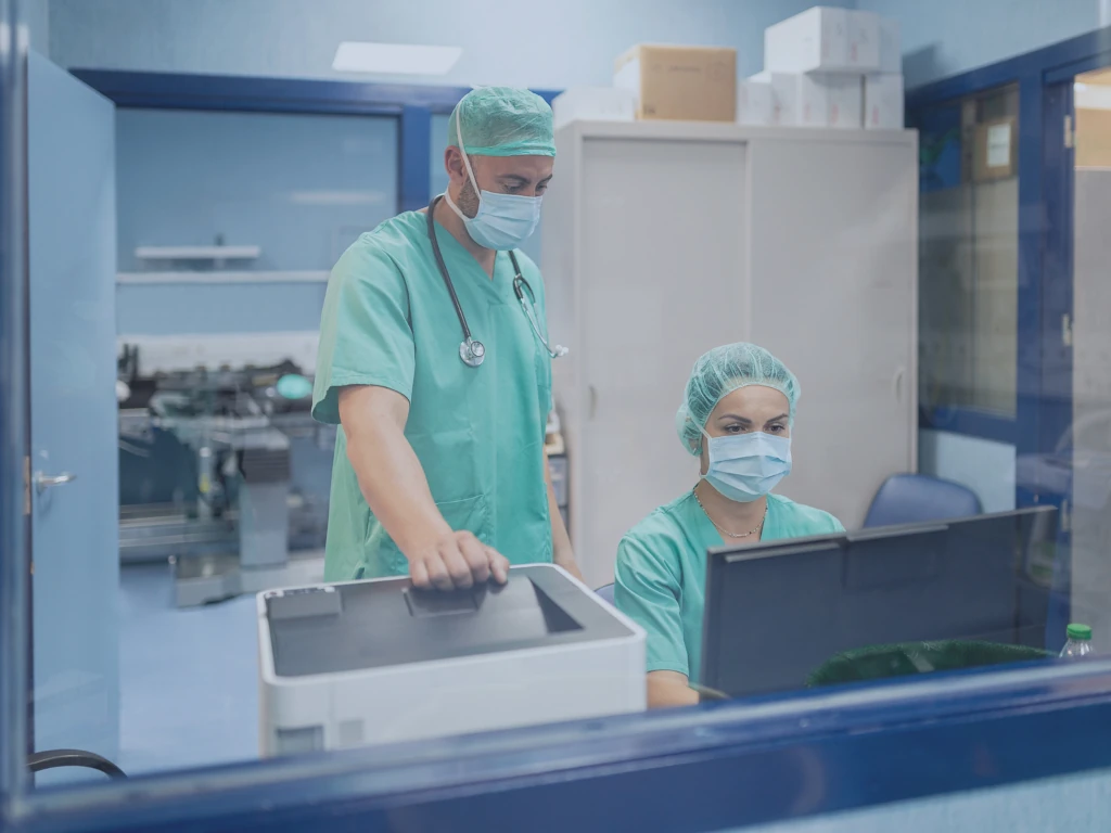 Eine Ärztin und ein Arzt im Krankenhaus betrachten Patientendaten auf einem Bildschirm