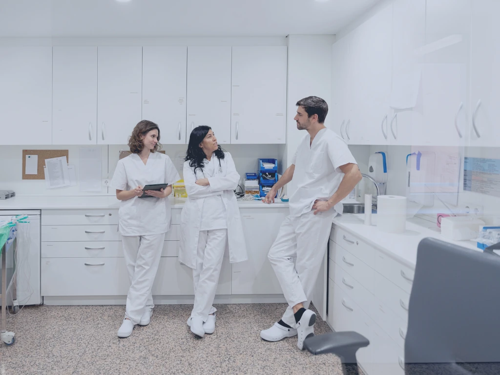 Erarbeitung von New Work Ansätzen Zwei Ärztinnen und ein Arzt im Krankenhaus besprechen sich über die Arbeitsorganisation.