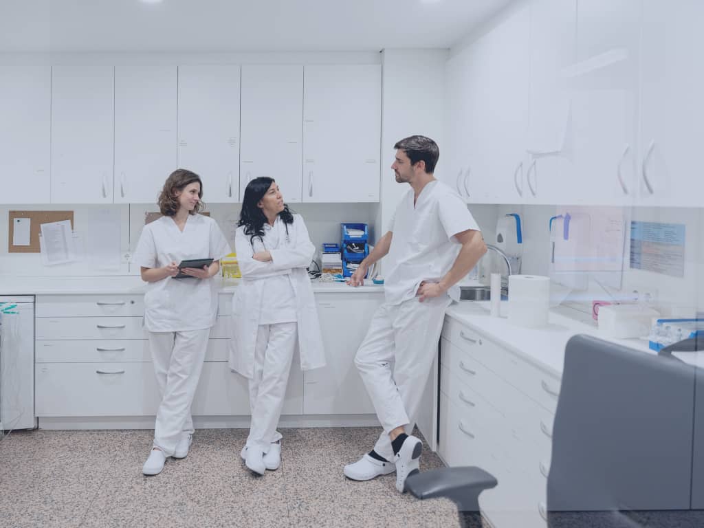 Mehrere Ärztinnen und Ärzte stimmen sich in der Klinik über eine Behandlung ab. Eine Ärztin nutzt das POLAVIS Patientenportal auf einem Pad.