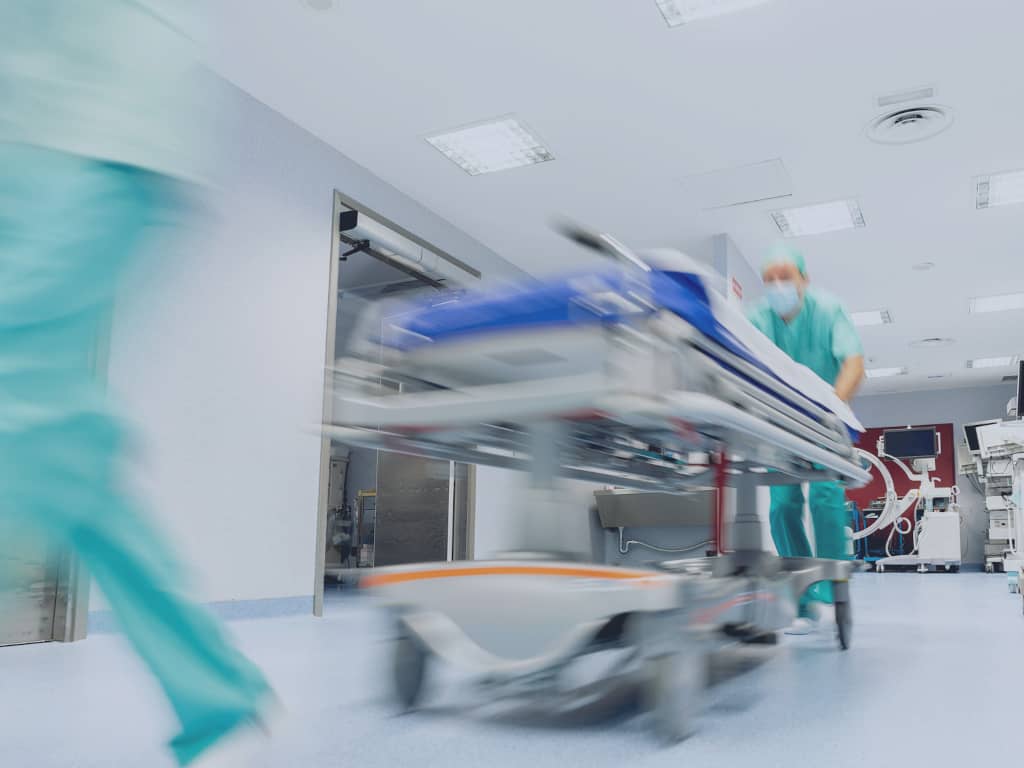 Ein Arzt schiebt rennend ein Patientenbett durch das Krankenhaus.