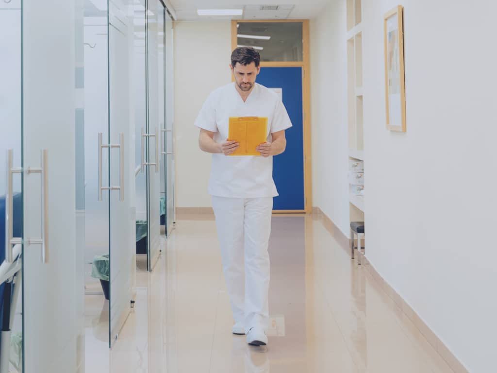 POLAVIS Whitepaper Krankenhaus der Zukunft Ein Arzt ließt Akten, während er den Gang in der Klinik entlangläuft.